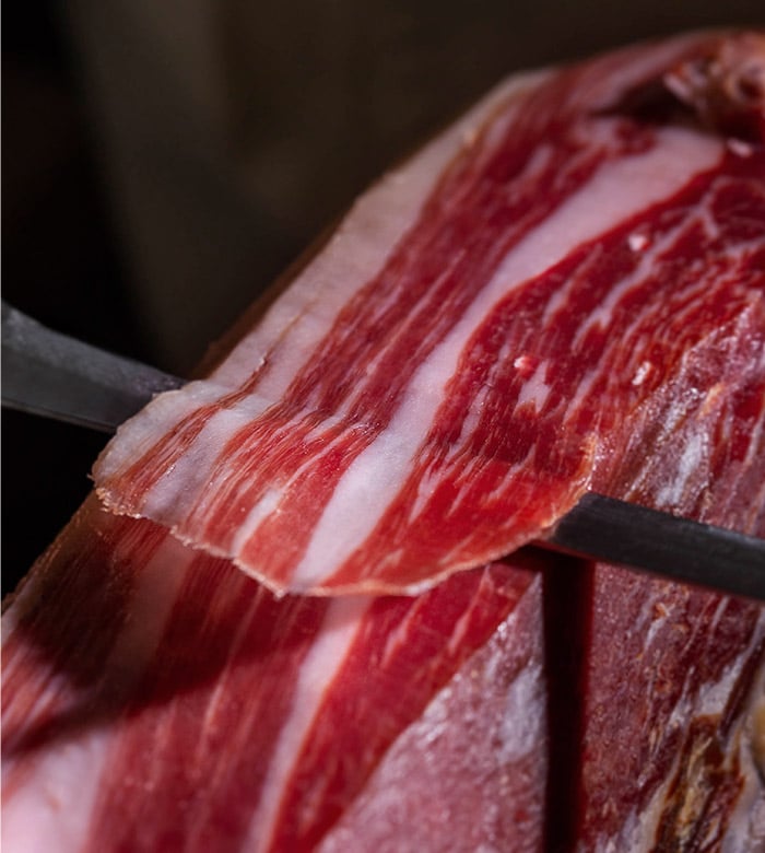 Coltello che taglia una fetta di prosciutto iberico allevato a ghiande FISAN