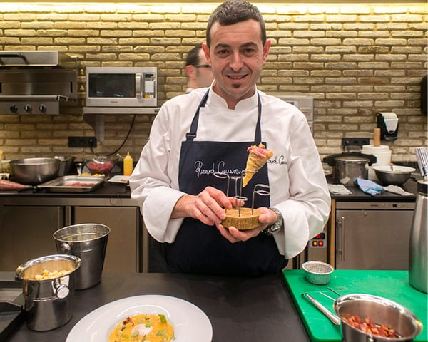 Chef Ricard Camarena en cocina con un Cucurucho de Masa Wanton, Jamón de Bellota y Presa de Bellota FISAN en la mano