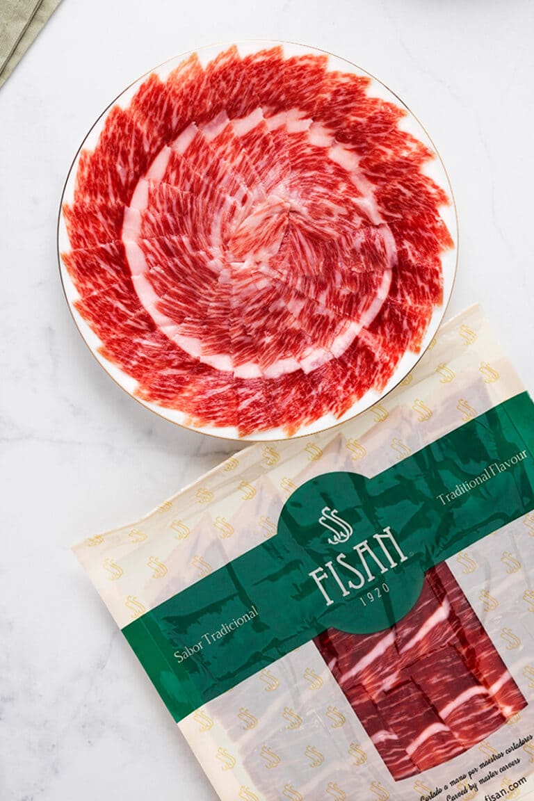 Jamón FISAN envasado al vacío junto a un plato de lonchas presentadas en espiral
