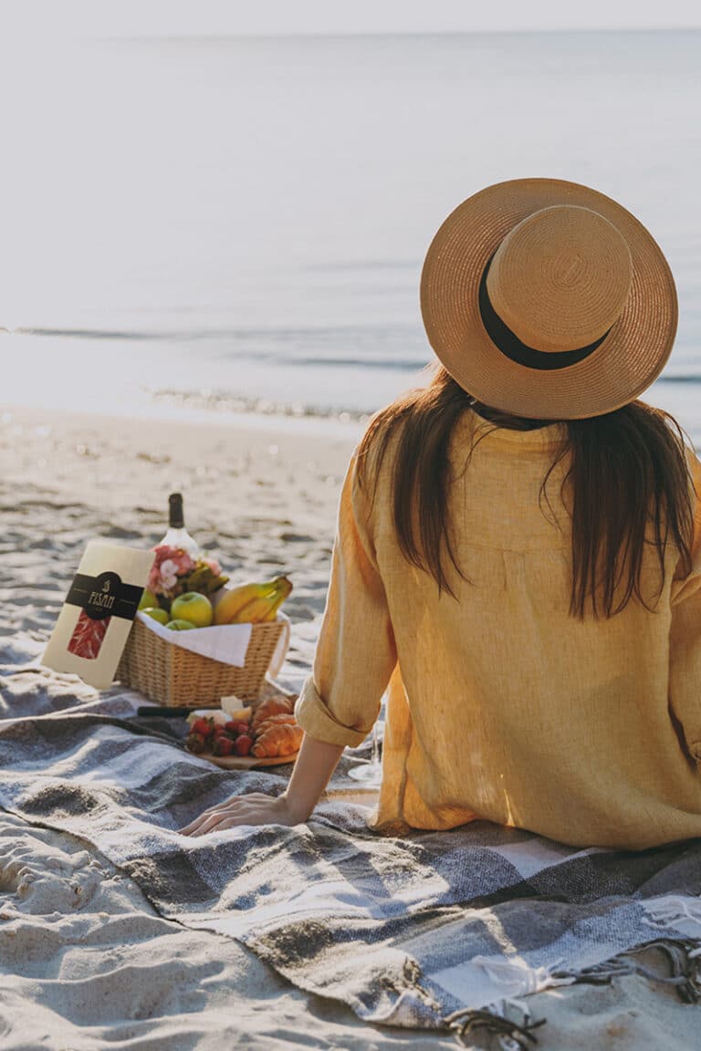 Mujer en la playa con picnic de jamón FISAN envasado al vacío