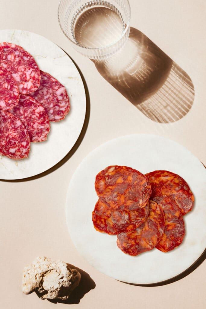 Rodajas de chorizo y salchichón ibérico FISAN 100% natural servidas en dos platos.