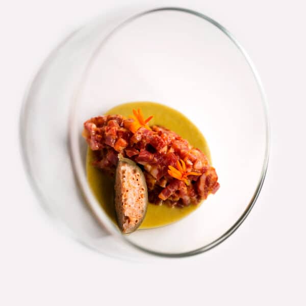 Tartar de Lomo de Presa de Bellota Ibérica FISAN, aliñado con encurtidos, alcaparras, yema asada y un gazpacho piparra con un toque ligeramente picante