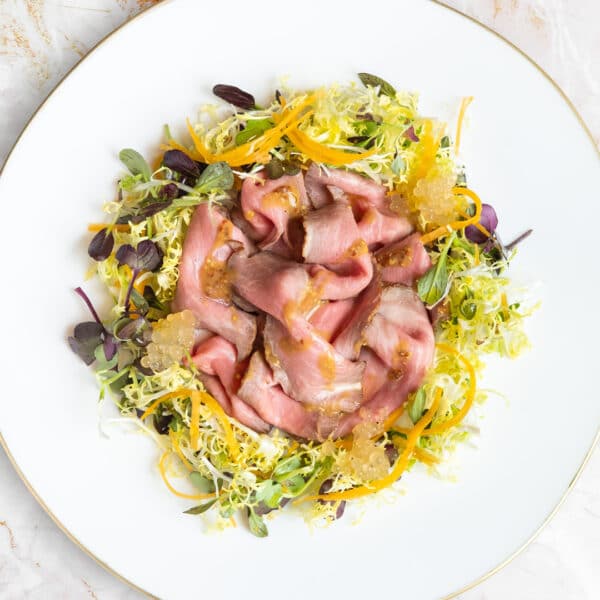 Presentación de la ensalada de presa ibérica FISAN con piñones verdes y calabaza